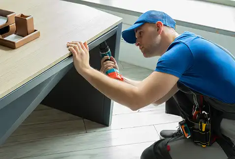 Un homme en salopette vérifie un bloc-notes debout à côté d'une camionnette de livraison remplie de cartons empilés. La scène dégage une impression d'efficacité et d'organisation.